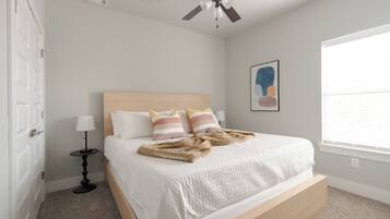Ein Schlafzimmer mit Bett, Deckenventilator, Fenster und Tür.
