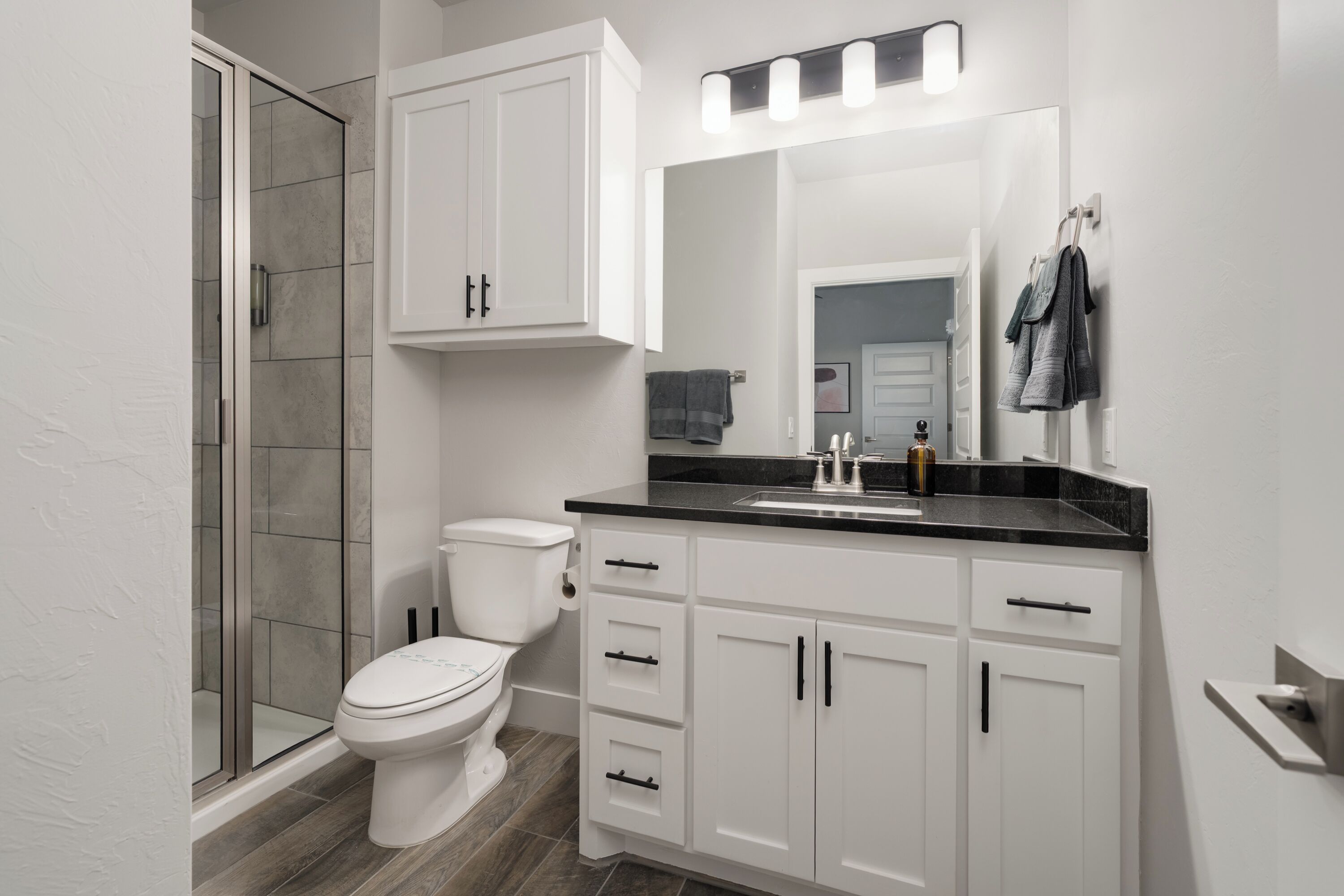 Un baño moderno con inodoro, ducha y tocador con lavabo.