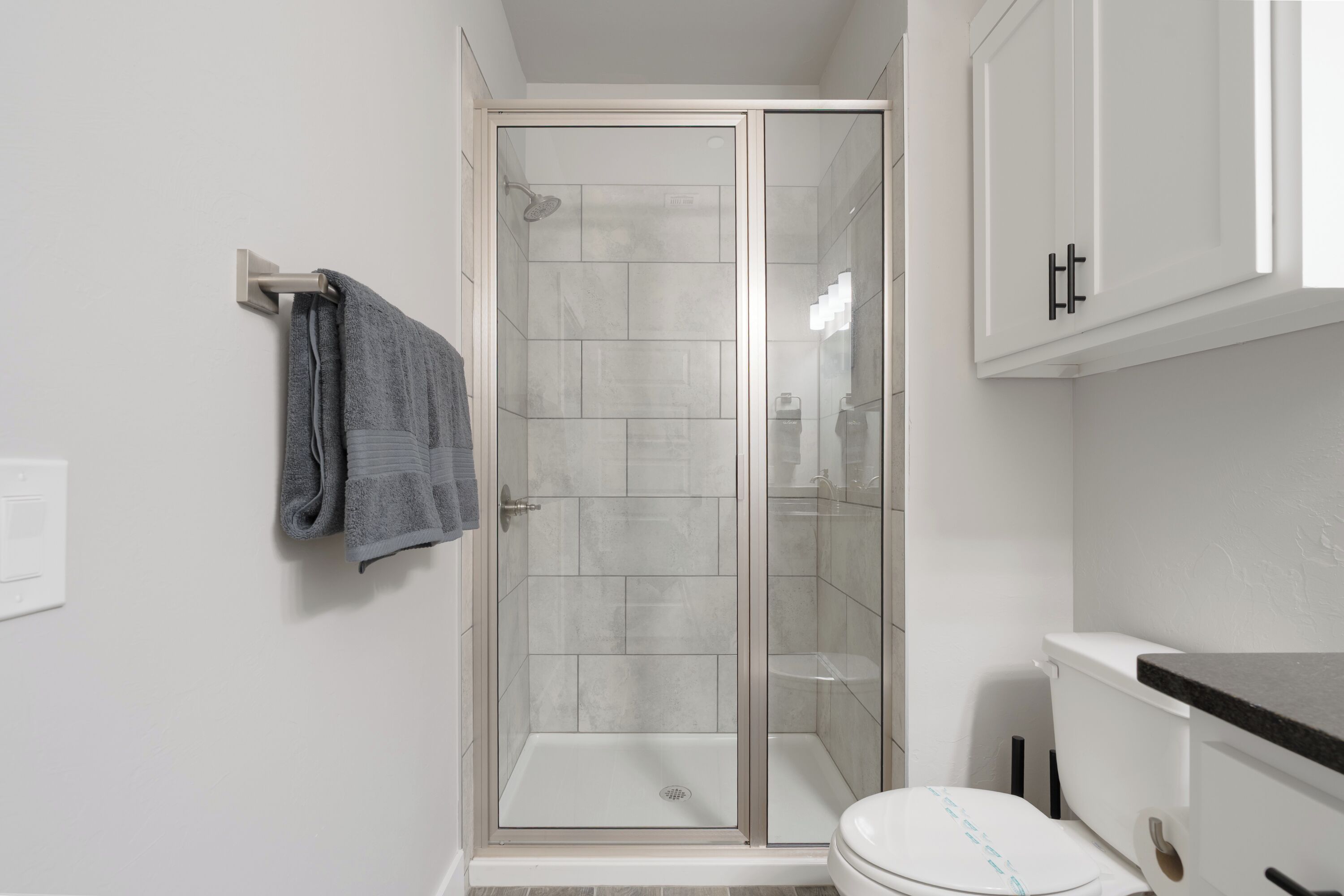 Un baño moderno con ducha acristalada, inodoro y un perchero para toallas.