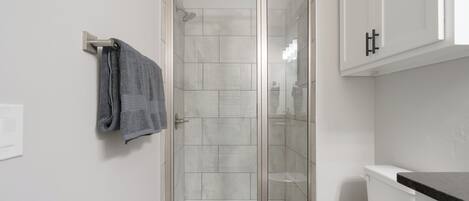 Un baño moderno con ducha acristalada, inodoro y un perchero para toallas.