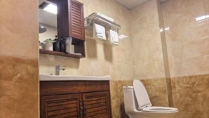 Une salle de bain comprenant des toilettes, un lavabo, un meuble en bois et une poubelle.
