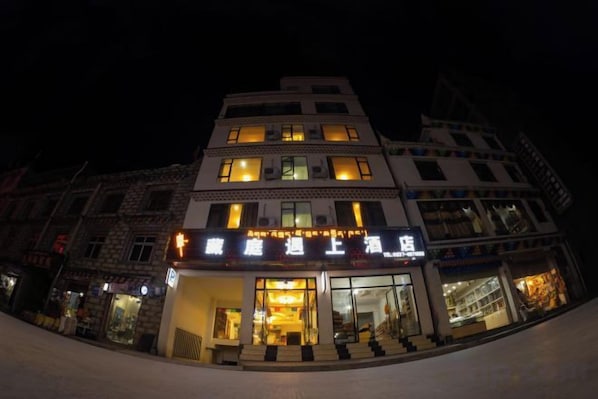 A multi-story building with illuminated signage, a staircase leading to the entrance, and a visible storefront.