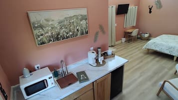 Een moderne keuken met een marmeren aanrechtblad, houten kastjes en een spoelbak. Boven de spoelbak hangt een schilderij en aan de muur is een decoratie van een hertenkop bevestigd.