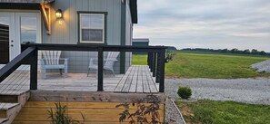 A wooden deck with two chairs, a wooden staircase, and a house with a number '2' sign.