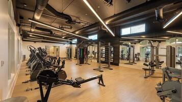 A gym with cardio equipment, weightlifting stations, and mirrors.
