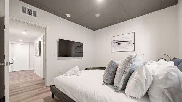Ein modernes Schlafzimmer mit einem großen Bett, einem Flachbildfernseher und einem Gemälde an der Wand.