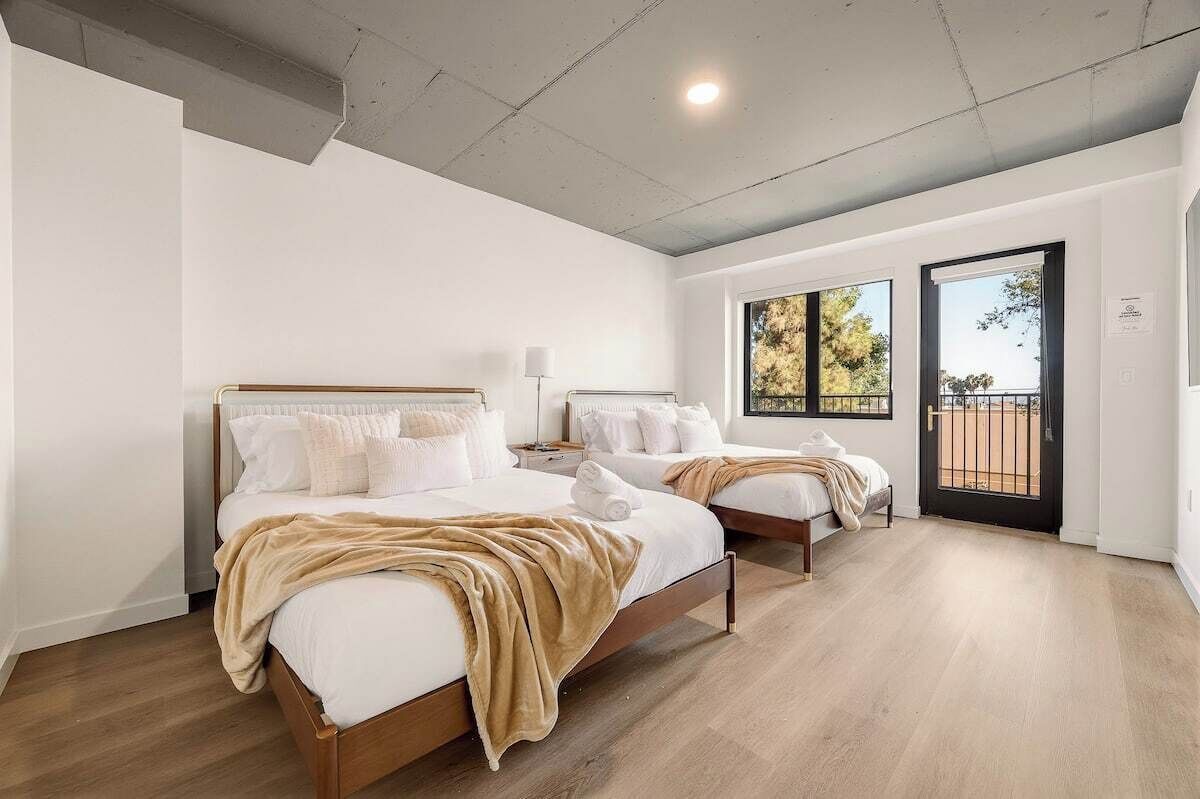 Habitación de hotel con dos camas, un balcón y vistas al exterior.