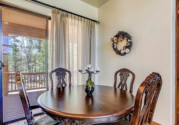 A dining area with a round wooden table, four chairs, a candelabra, and a wall decoration.