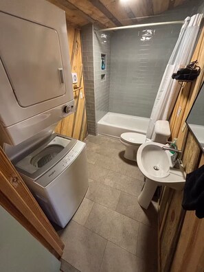 Ett litet badrum med tvättmaskin, toalett och handfat.