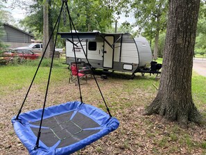 A blue trampoline in a wooded area with a Coleman RV in the background. - The Escape @ Vanderosa (Montgomery County)