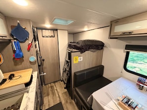 A compact interior with a bunk bed, a small kitchenette, and a window providing a view. - The Escape @ Vanderosa (Montgomery County)