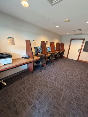 A conference room with long tables, chairs, and a projector.