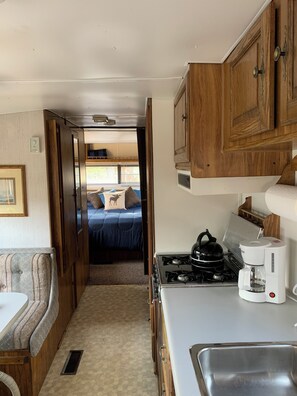 A compact RV kitchen with a stove, coffee maker, and a sink. A bunk bed is visible in the background. - Mag River Paradise
Paddle • Fish • Swim • Relax
Experience the Magnetawan
River (Burk's Falls)