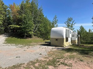 A recreational vehicle parked in a natural setting with a gravel path leading to it.