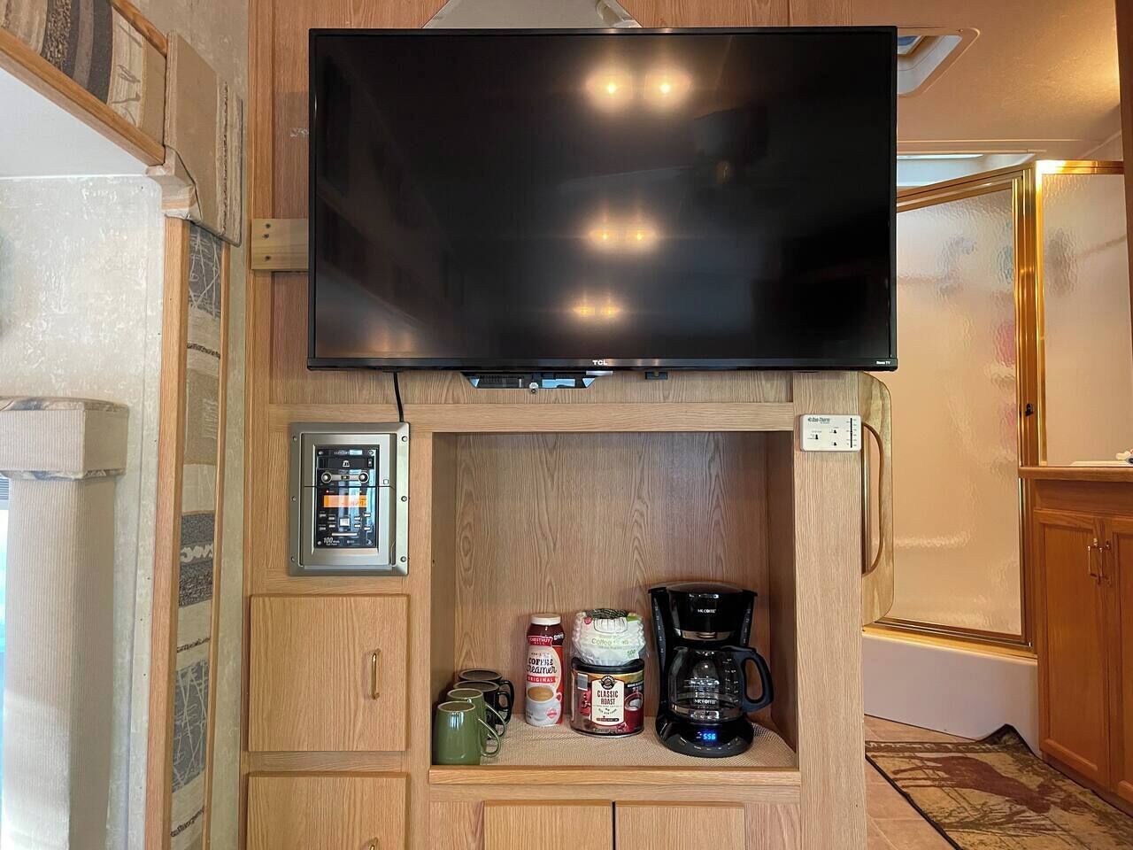 Una kitchenette con televisor de pantalla plana, cafetera y molinillo de café.