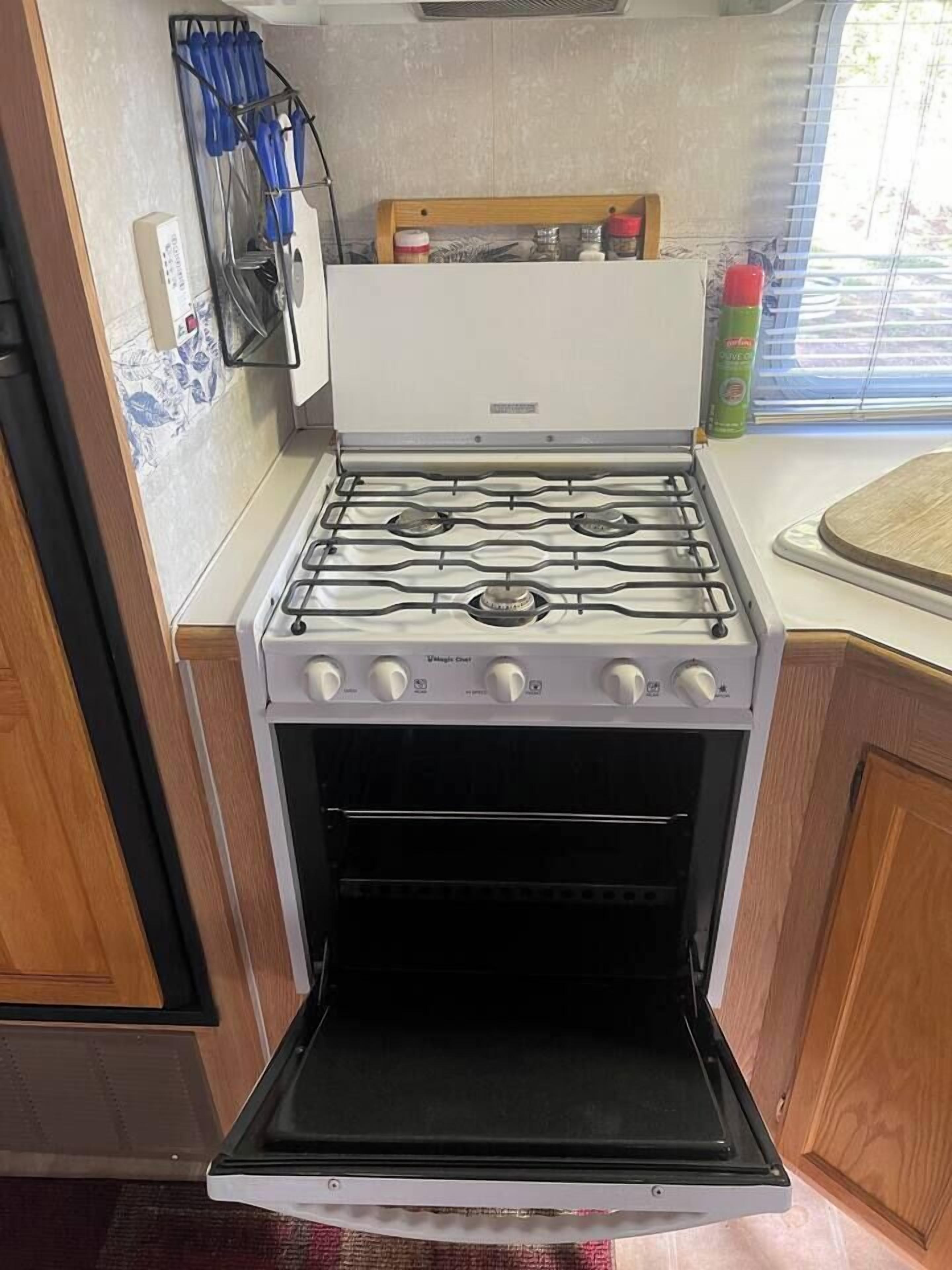 A kitchen with a stove, oven, and a window with blinds.