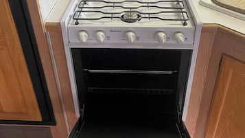 A kitchen with a stove, oven, and a window with blinds.