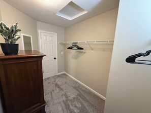 A hallway with a door, a plant, a coat rack, and a carpeted floor.
