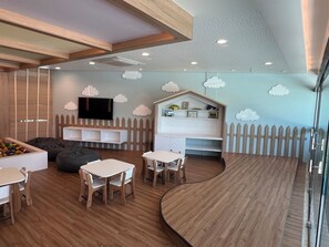 A children's playroom with a wooden floor, white tables, bean bags, and a playhouse. - ⭐ Muro Alto Beach Resort near Porto de Galinhas | Pool & Garden (Ipojuca)
