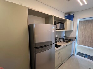A compact kitchen with a built-in refrigerator, a microwave, and a sink. - ⭐ Muro Alto Beach Resort near Porto de Galinhas | Pool & Garden (Ipojuca)