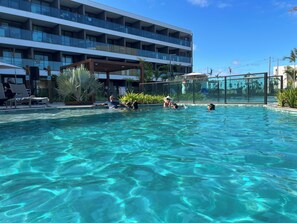 A swimming pool with clear water, surrounded by lounge chairs and palm trees. - ⭐ Muro Alto Beach Resort near Porto de Galinhas | Pool & Garden (Ipojuca)