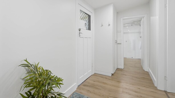 A hallway with white walls, wooden flooring, and a potted plant. - Apple Court Retreat – 3 Bedroom – Access to Huon River (Huonville)