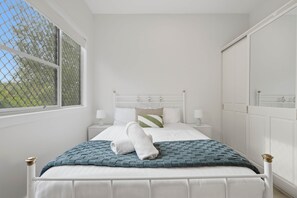 Ein Schlafzimmer mit Bett, Nachttischen, einem Fenster mit Blick und einem Kleiderschrank.