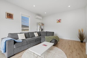 Ein modernes Wohnzimmer mit einem grauen Ecksofa, einem weißen Couchtisch und einem Bücherregal.