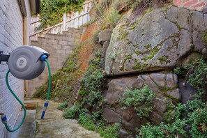 A water fountain with a hose, a stone wall, and a wooden fence. - Cottage on Quayle - 3 Bedroom in Sandy Bay (Sandy Bay)