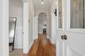 A hallway with wooden flooring, white walls, and a door with a decorative knob. - Cottage on Quayle - 3 Bedroom in Sandy Bay (Sandy Bay)