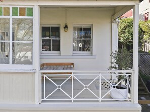 A white porch with a bench, two windows, and a potted plant. - Cottage on Quayle - 3 Bedroom in Sandy Bay (Sandy Bay)
