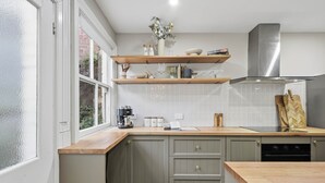 Een keuken met een ingebouwde oven, een koffieapparaat en een houten aanrecht.