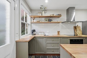 A kitchen with a built-in oven, a coffee machine, and a wooden countertop. - Cottage on Quayle - 3 Bedroom in Sandy Bay (Sandy Bay)