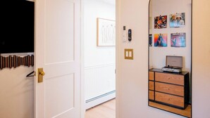 A hallway with a white door, a wall-mounted light switch, and a small cabinet with a turntable. - Retro Luxe Suite, Downtown Manchester near Hartford Sleeps 4! New! (Manchester)