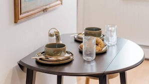 A dining table with a framed artwork, a bowl, a glass, and a candle holder. - Retro Luxe Suite, Downtown Manchester near Hartford Sleeps 4! New! (Manchester)