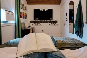 A bedroom with a bed, an open book, a flat-screen TV, a dresser, and a mirror. - Retro Luxe Suite, Downtown Manchester near Hartford Sleeps 4! New! (Manchester)