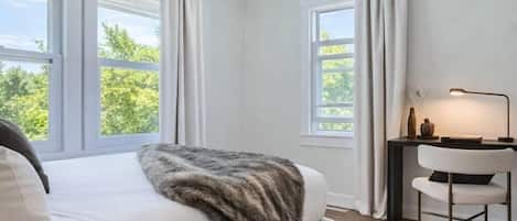 A bedroom with a bed, a desk with a chair, and a ceiling fan.