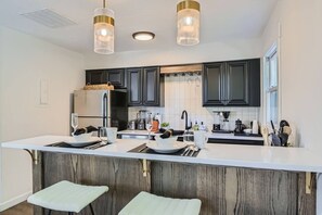 A modern kitchen with dark cabinets, a white countertop, and two pendant lights. - Walk Everywhere - Hot Tub - Free Parking (Park City)