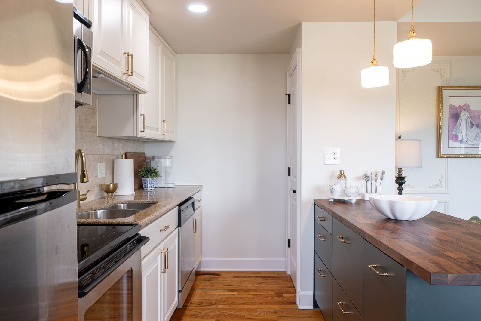 A modern kitchen with stainless steel appliances, white cabinetry, and a wooden countertop.