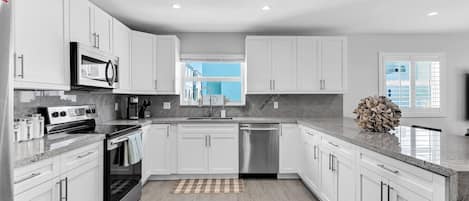 Una cocina moderna con armarios blancos, electrodomésticos de acero inoxidable y encimera de granito.