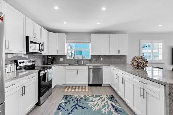 A modern kitchen with white cabinetry, stainless steel appliances, and a granite countertop.