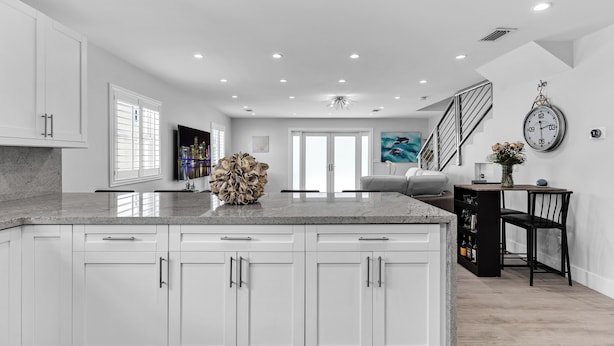 A modern kitchen with white cabinetry, a granite countertop, and a central island.