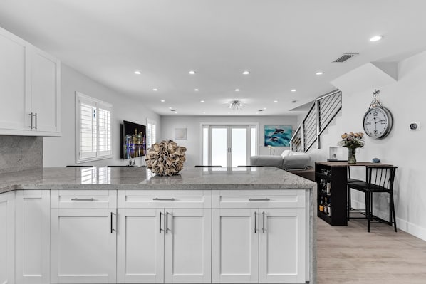A modern kitchen with white cabinetry, a granite countertop, and a central island.