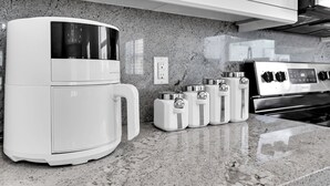 A kitchen with a coffee maker, a stove, and a set of condiment containers on the counter.