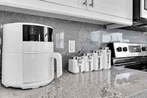 A kitchen with a coffee maker, a stove, and a set of condiment containers on the counter.