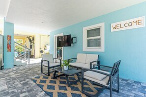 A reception area with a blue wall, a welcome sign, a sofa, two chairs, a coffee table, and a TV mounted on the wall.
