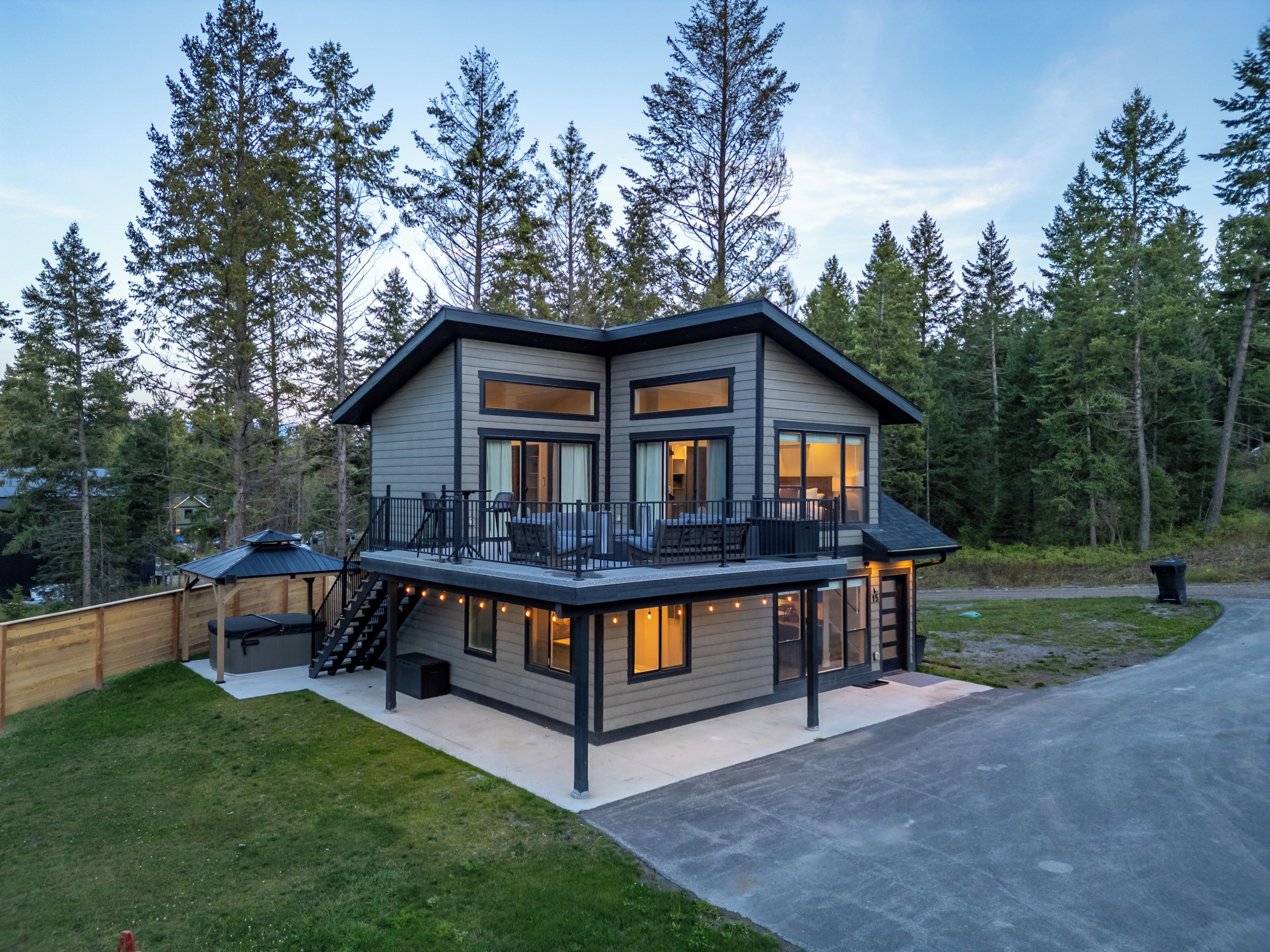 A modern two-story house with a balcony, large windows, and a deck area.