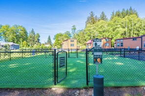 Un parco recintato per cani con un'indicazione per la postazione di raccolta deiezioni canine.