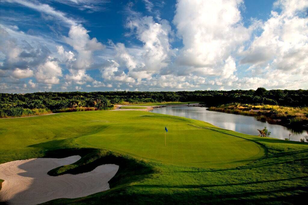 A golf course with a pond, sand bunkers, and a flagstick.