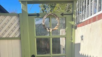 A green door with a decorative wreath, a lattice fence, and a white wall with a textured pattern.